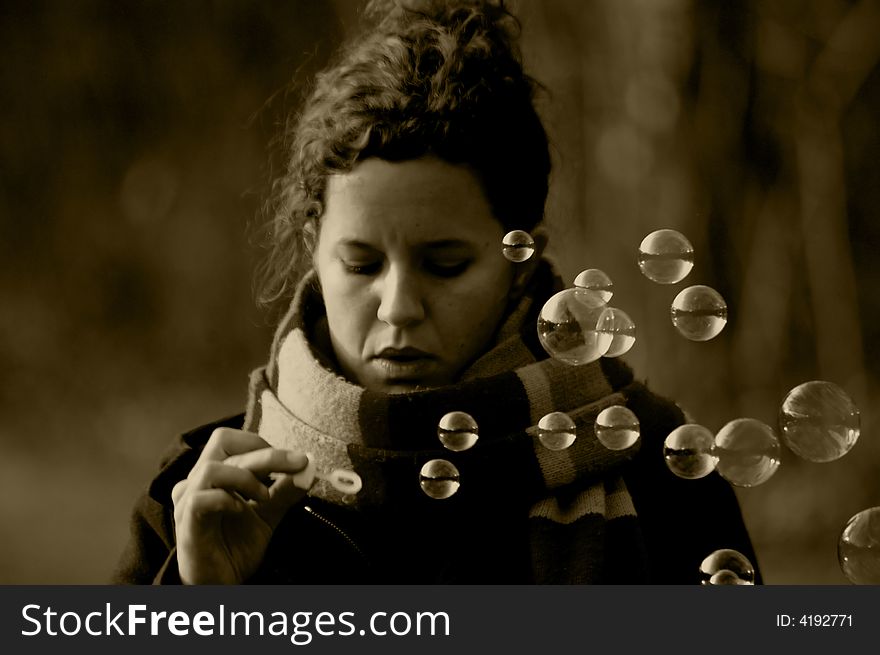 A young woman playing with soap bubbles (in sepia). A young woman playing with soap bubbles (in sepia)
