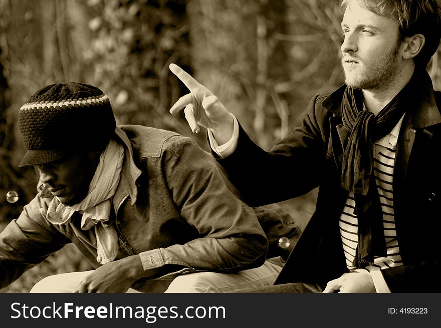 Portrait of two friends seated on a garden seat : a red-haired man and a rasta man. Portrait of two friends seated on a garden seat : a red-haired man and a rasta man.