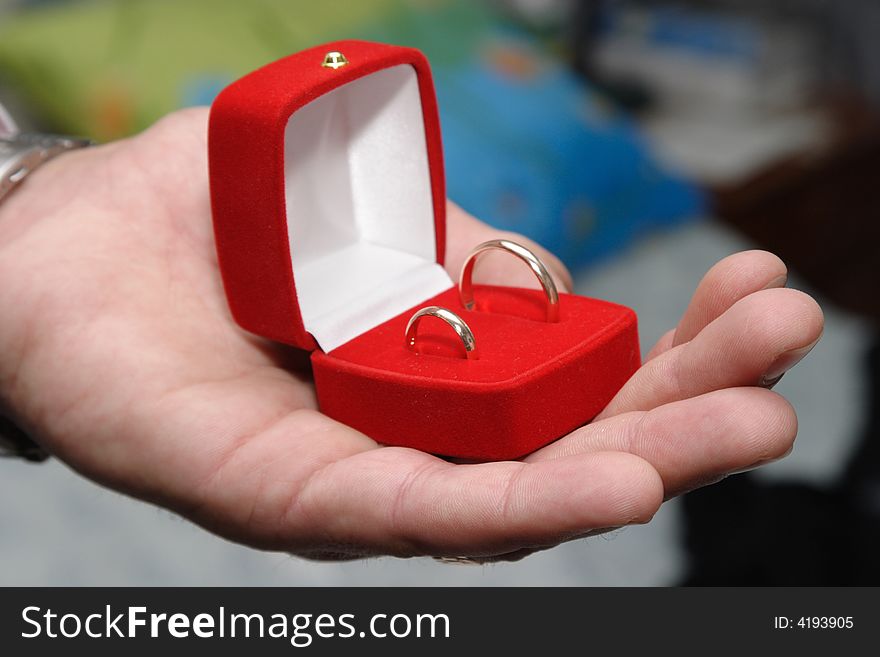 The man's hand holding a box with rings. The man's hand holding a box with rings