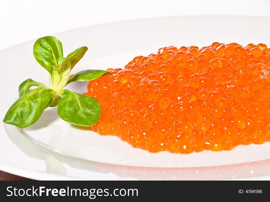 Red caviar served on a white plate. Close-up. White background. Red caviar served on a white plate. Close-up. White background.