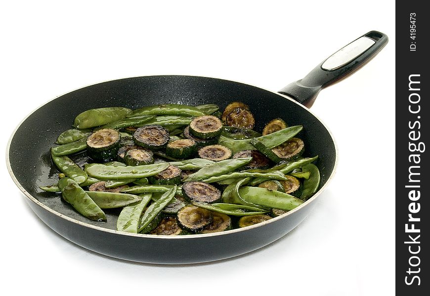 A frying pan filled with green peas and 
zucchini. A frying pan filled with green peas and 
zucchini