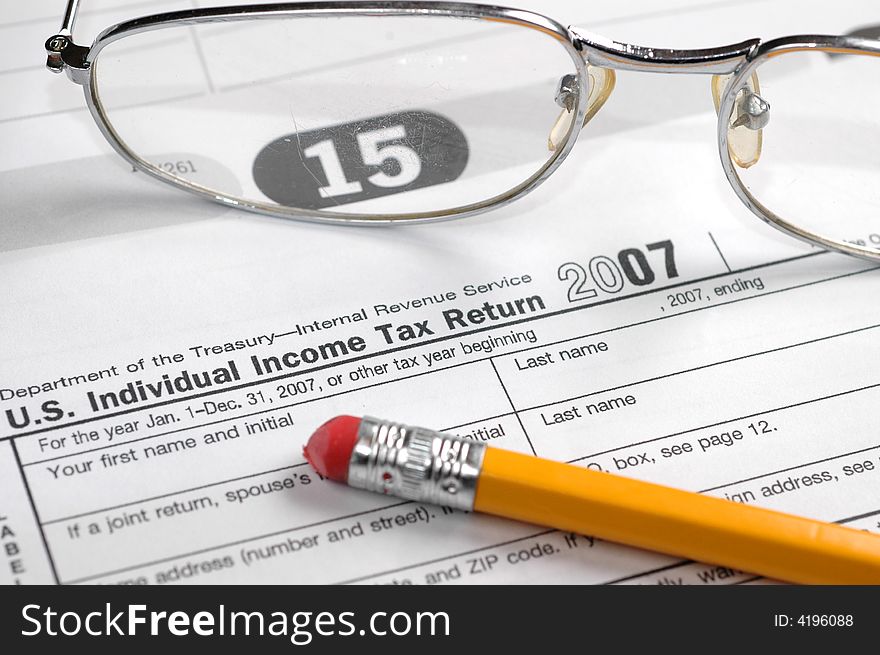 income tax form, with pencil and glasses. On a calender showing the april 15th tax deadline. income tax form, with pencil and glasses. On a calender showing the april 15th tax deadline.