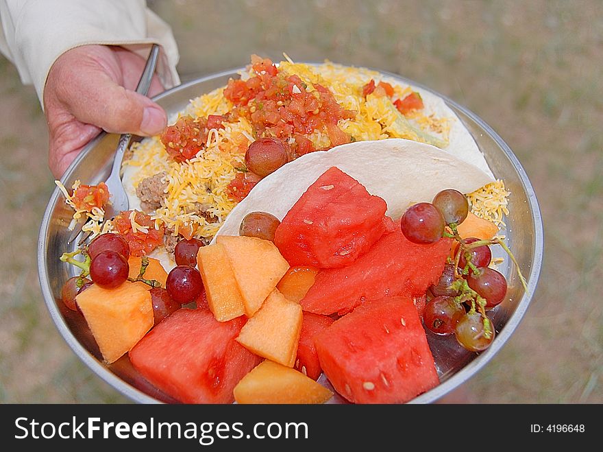 Plate full of fruit and a breakfast taco. Plate full of fruit and a breakfast taco