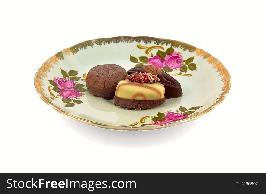 Three chocolate candies on a plate with white background. Three chocolate candies on a plate with white background