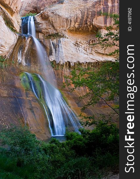 Waterfall against red rock in tree covering of Escalante, Utah