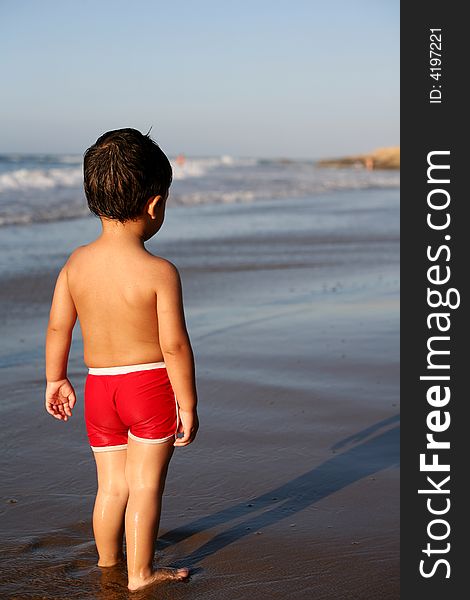 A young boy at the beach thinking what to do next. A young boy at the beach thinking what to do next