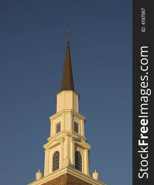 Church Steeple with a cross at the top against a blue sky. Church Steeple with a cross at the top against a blue sky