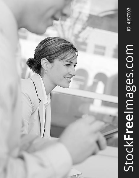 Side view of two well-dressed businesspeople standing, woman is smiling. Side view of two well-dressed businesspeople standing, woman is smiling