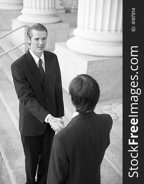 Two businessmen standing on steps shaking hands. Two businessmen standing on steps shaking hands