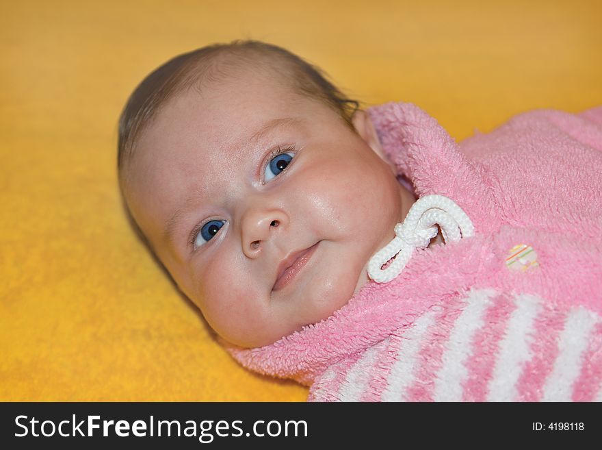 Small baby in a warm suit on yellow