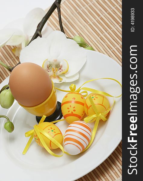 Nature egg with easter colored eggs and orchid on a table.