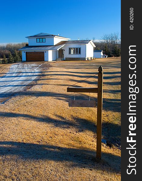 A rural home with a sign marking the entrance to the lot. A rural home with a sign marking the entrance to the lot.