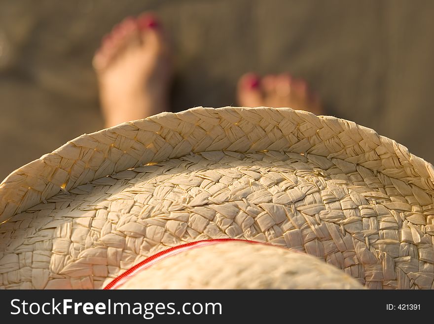 Picture of a straw hat on a women over her painted toes. Picture of a straw hat on a women over her painted toes