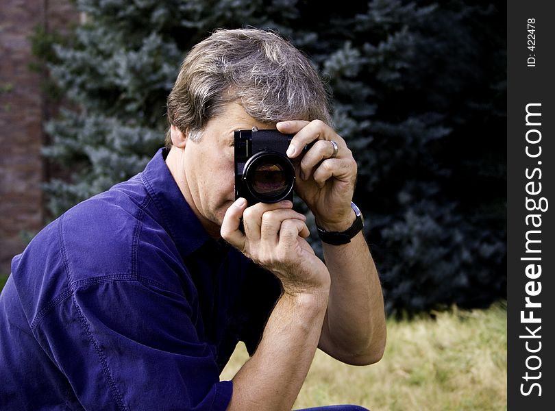 A man pointing the rangefinder camera lens at the viewer. A man pointing the rangefinder camera lens at the viewer.