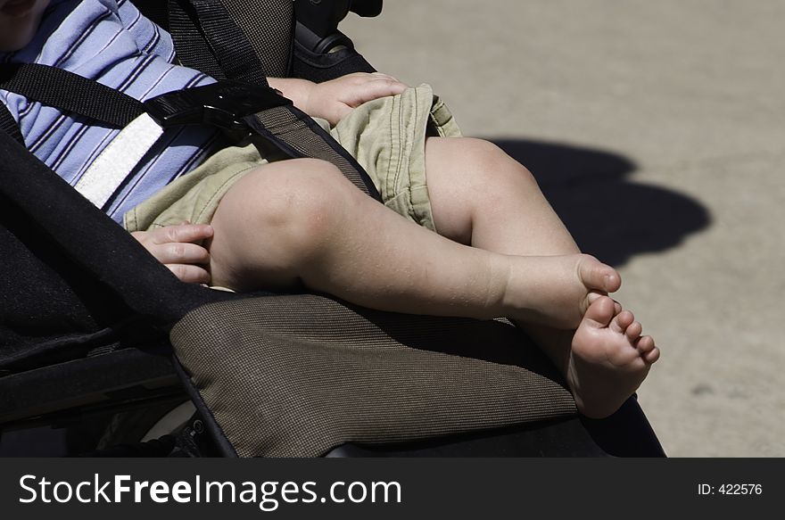 A baby in the stroller suns his toes and watches them turn pink from the intensive sun. Where's the sunscreen?. A baby in the stroller suns his toes and watches them turn pink from the intensive sun. Where's the sunscreen?