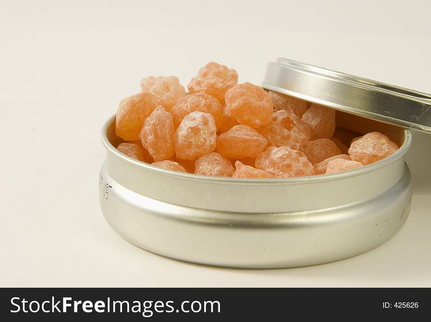 Tangerine rock candies in a silver round box isolated for text.