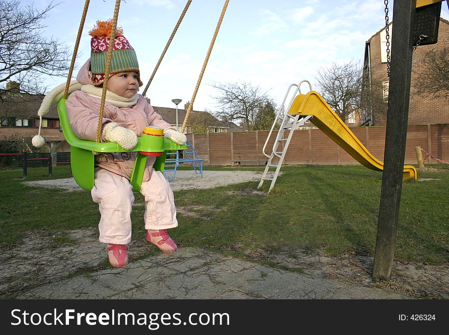 Little Girl on a swing at the playground in the winter time. Little Girl on a swing at the playground in the winter time.