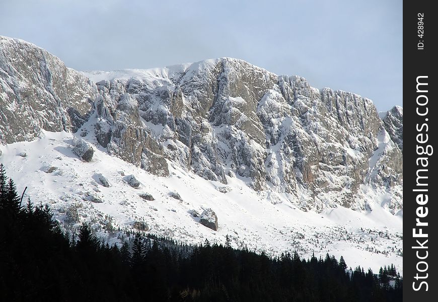 Mountain Peaks Covered With Snow And Little Forest Downhill