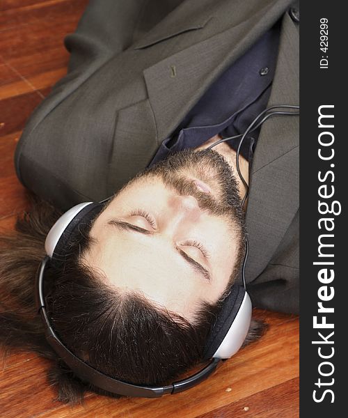 Music executive lying on the floor listening to music with headphones