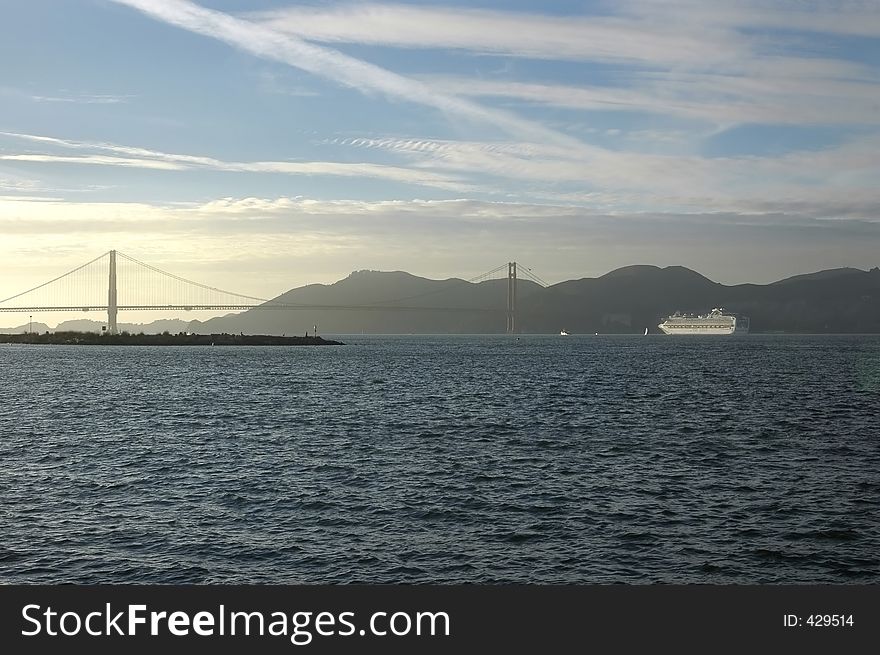 San Francisco Bay at sunset with Golden Gate Bridge and cruise ship in background.