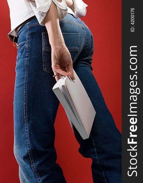 Woman in Jeans with book on outstretched arm. Perspective from behind and low. Without upper body. Woman in Jeans with book on outstretched arm. Perspective from behind and low. Without upper body.