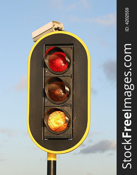 Black board traffic light with observation camera against some clouds. Black board traffic light with observation camera against some clouds.