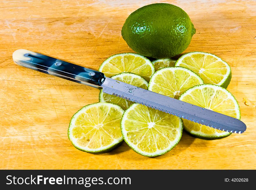 Limes sliced on a board with a knife. Limes sliced on a board with a knife