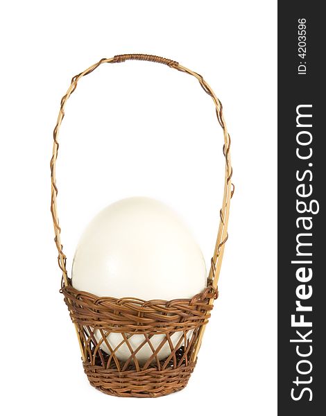 Ostrich egg in a wicker basket on white background