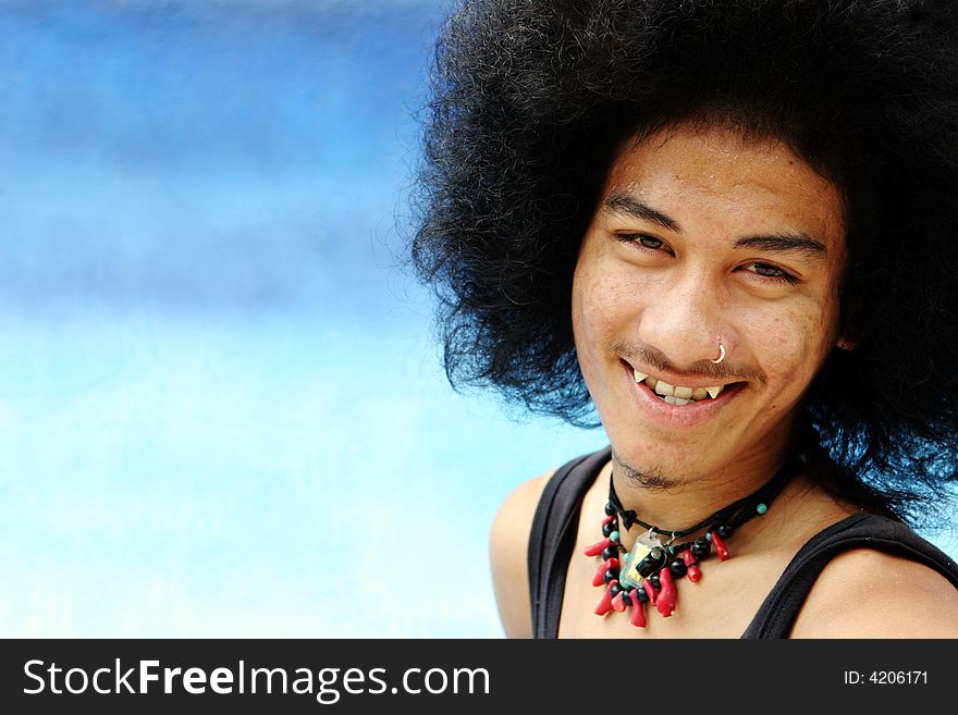 Portrait of a young Thai man with an afro isolated on blue.