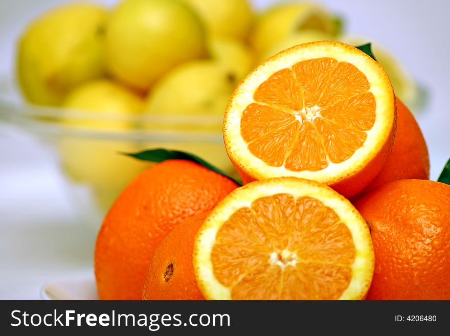 A pile of oranges with two slices and lemons in the background. A pile of oranges with two slices and lemons in the background.