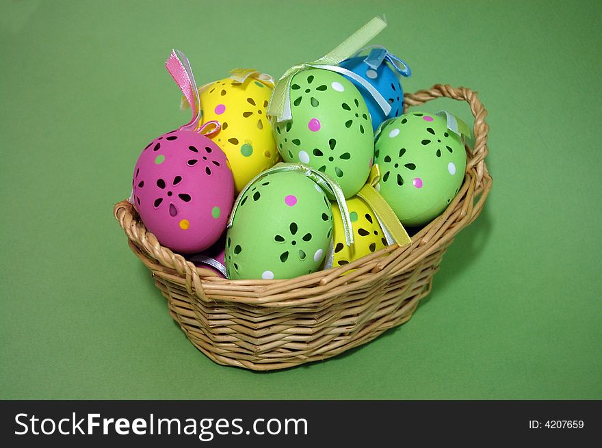 Closeup of colorful, beautifully crafted easter eggs in a wicker basket on a green background