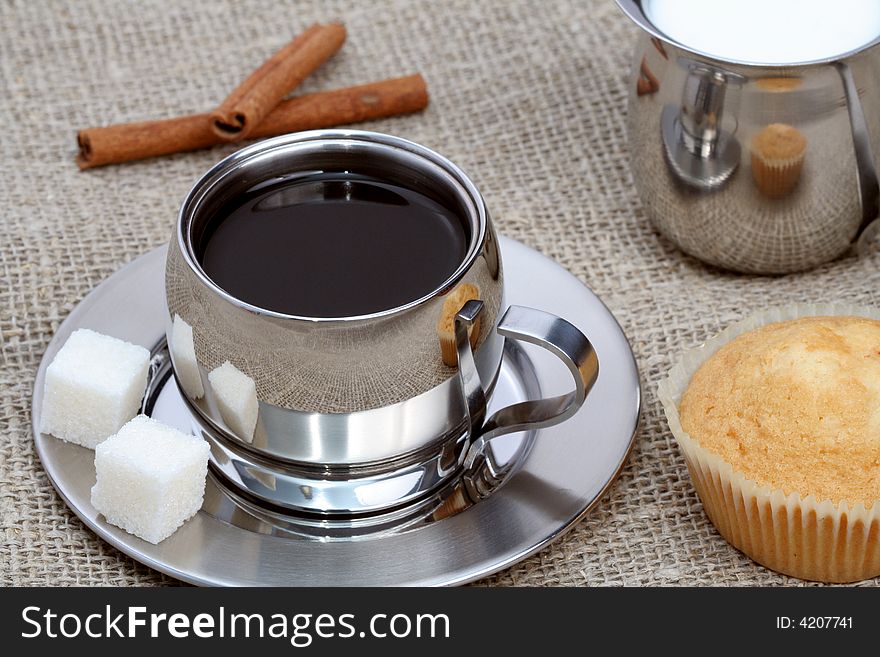 Cup of black coffee with muffin, milk and cinnamon