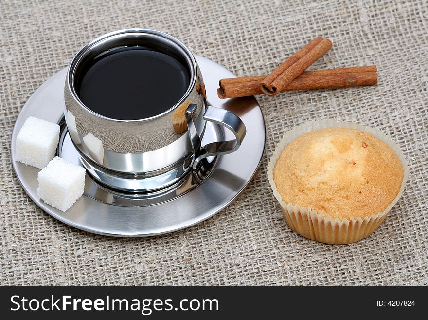 Cup of black coffee with muffin and cinnamon