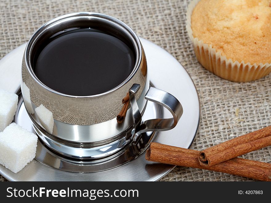 Cup of black coffee with muffin and cinnamon