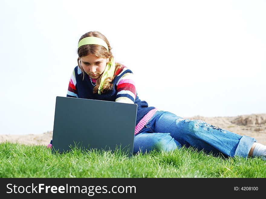 Young girl is working on laptop at outdoor location. Young girl is working on laptop at outdoor location