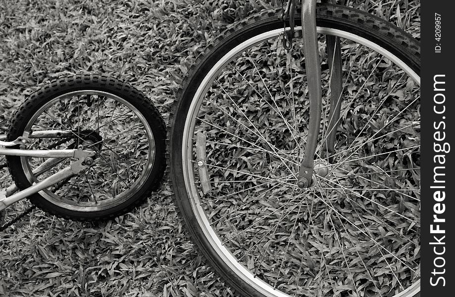 Black and white image of bicycle wheels against grass background emphasizing the pleasure of sports