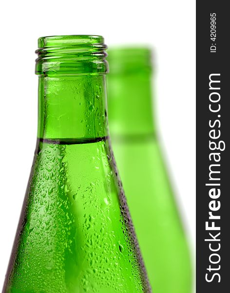 Bottled water in green, condensation-covered bottles; differential focus