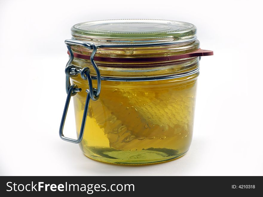 Honey and honeycomb in closed kitchen jar; isolated on white ground. Honey and honeycomb in closed kitchen jar; isolated on white ground