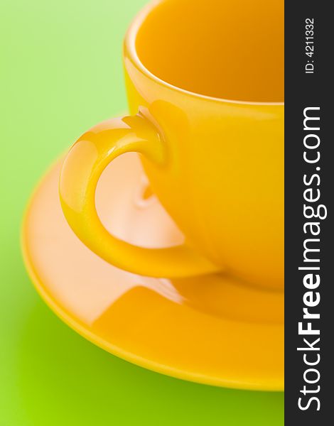 Empty yellow coffee cup over a light green background