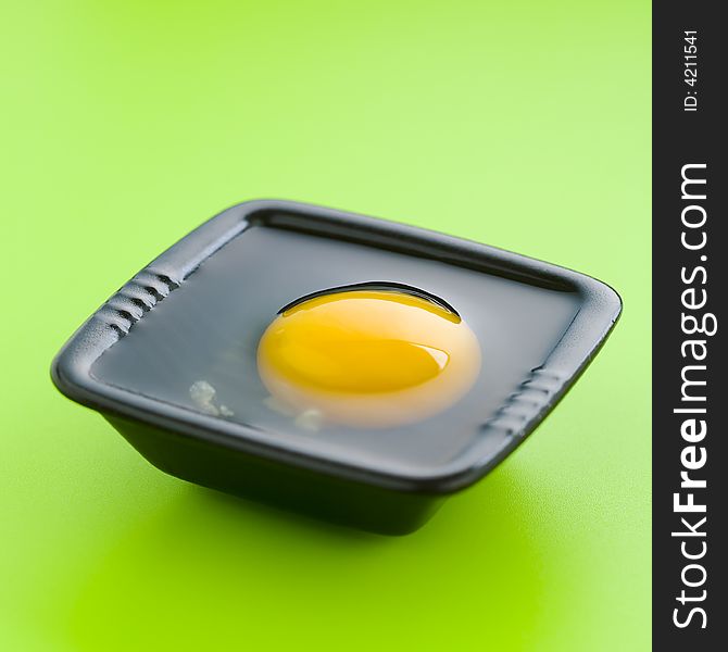 Egg on the black cup over a green table. Egg on the black cup over a green table