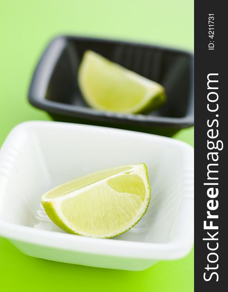 Lime halves in the small cups over light green background