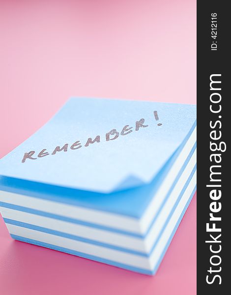 Pile of sticky notes with meeting reminder text over a pink table