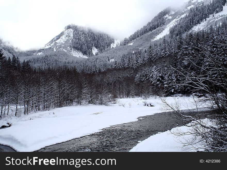 A stream flowing through snow covered mountains. A stream flowing through snow covered mountains.