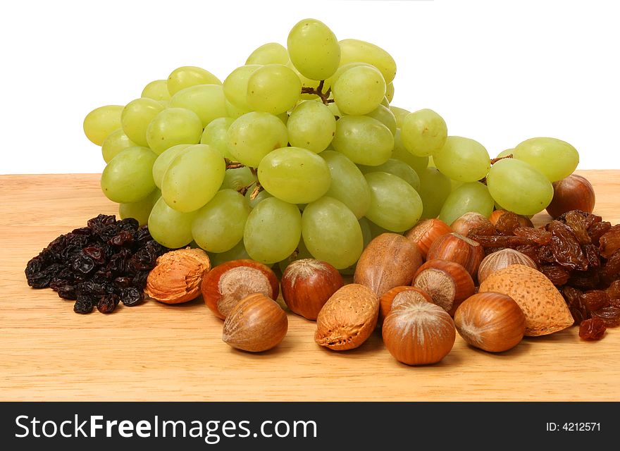 Fruit and nuts on wooden board against white