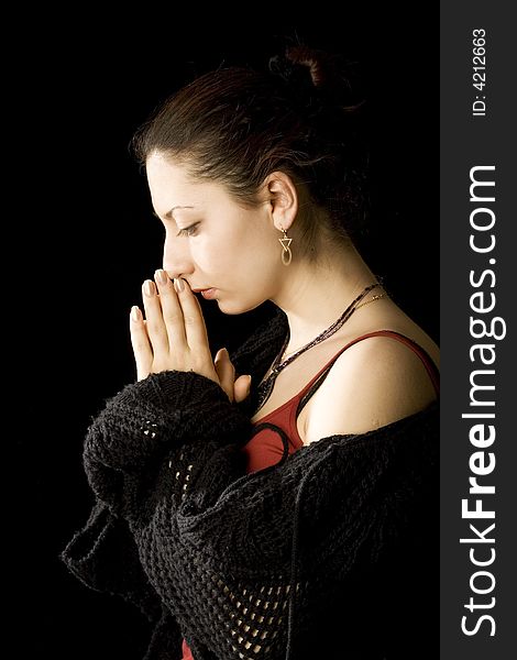 Portrait of young beautiful woman on black background. She stand sideview to a viewer with closed eyes and humbly hold palms near face like  offering up a prayer. Portrait of young beautiful woman on black background. She stand sideview to a viewer with closed eyes and humbly hold palms near face like  offering up a prayer