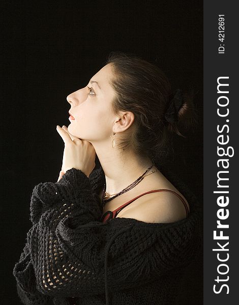 Portrait of a young beautiful woman on a black background, she stand sideview to a viewer, suuport her chin with a hand and look upward. She looks stylish, proudly and serenely. Portrait of a young beautiful woman on a black background, she stand sideview to a viewer, suuport her chin with a hand and look upward. She looks stylish, proudly and serenely.