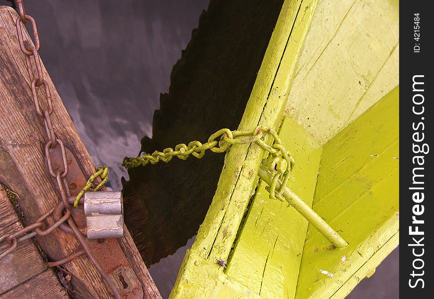 Old green boat chained to a pier. Old green boat chained to a pier