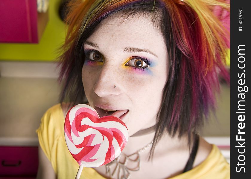 Alternative Girl in a Colorful Kitchen with a Heart Lollipop. Alternative Girl in a Colorful Kitchen with a Heart Lollipop