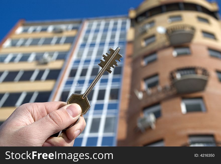 On a background of a modern brick house, hand with keys from an apartment. On a background of a modern brick house, hand with keys from an apartment.