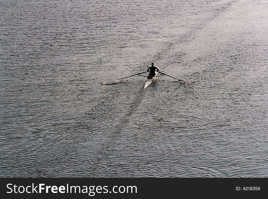 A lone rower on a river early in the morning